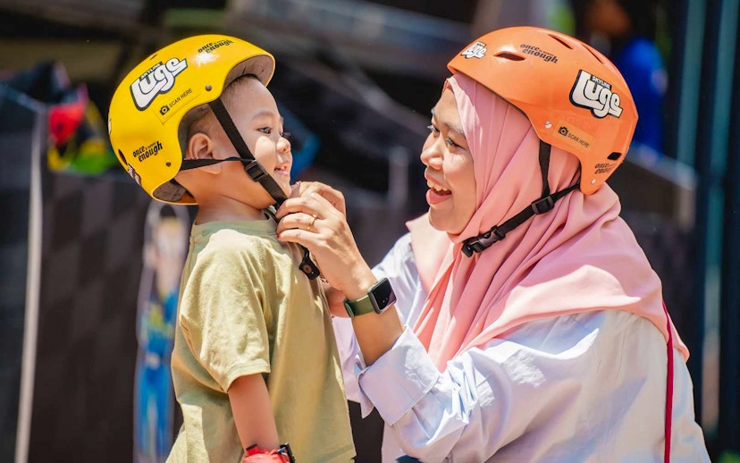 Woman adjusting child's helmet at The Skyline Luge, Kuala Lumpur.