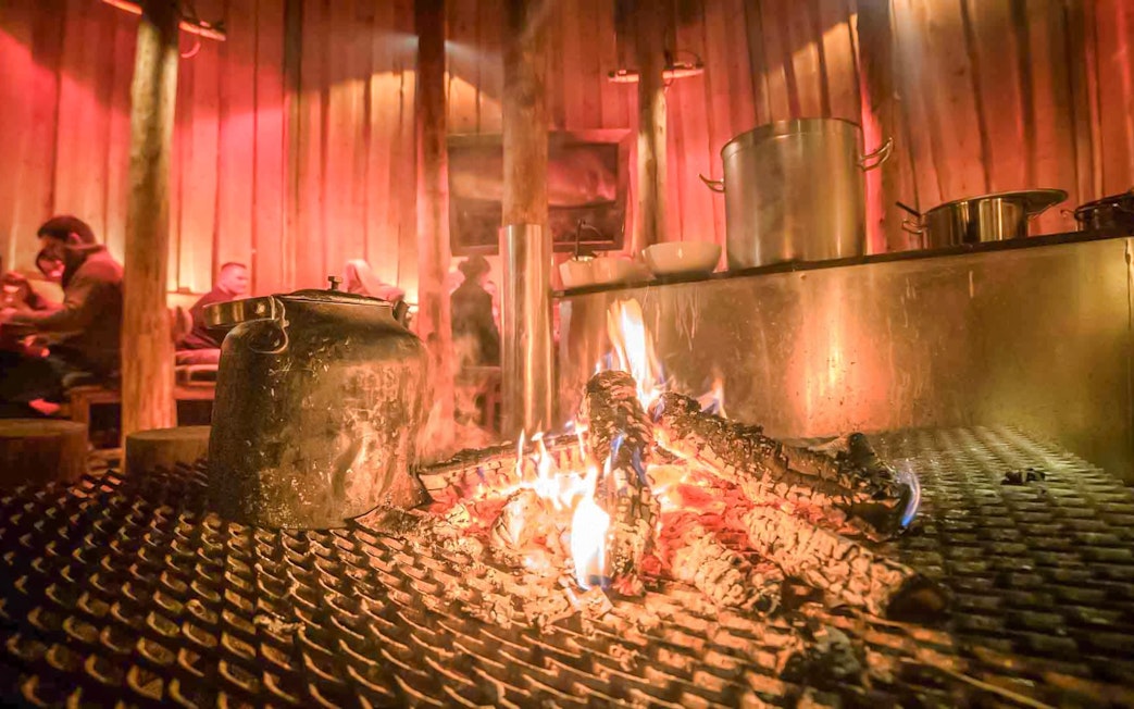 Warm drinks by the fire in a traditional Gamme hut, Tromso.
