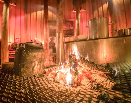 Warm drinks by the fire in a traditional Gamme hut, Tromso.