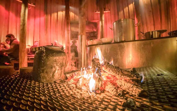Warm drinks by the fire in a traditional Gamme hut, Tromso.