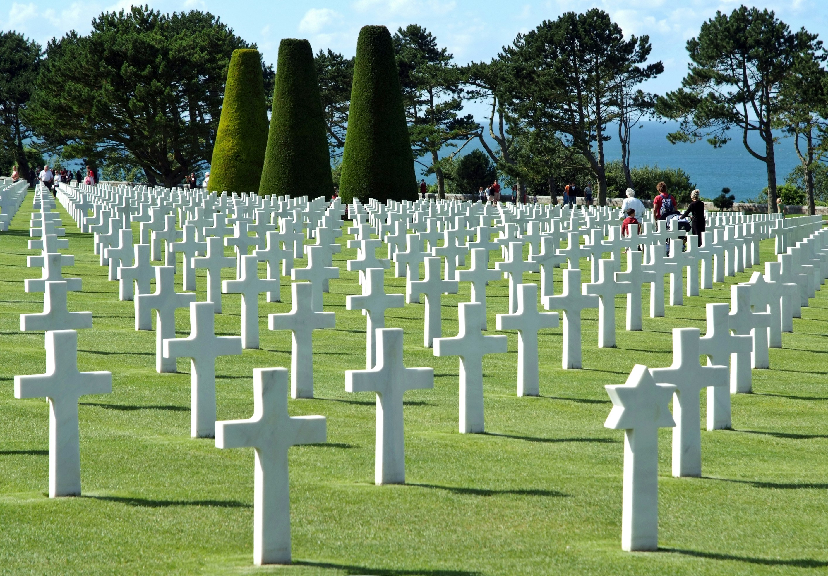 Visitors walking among white crosses at Normandy American Cemetery near Omaha Beach.