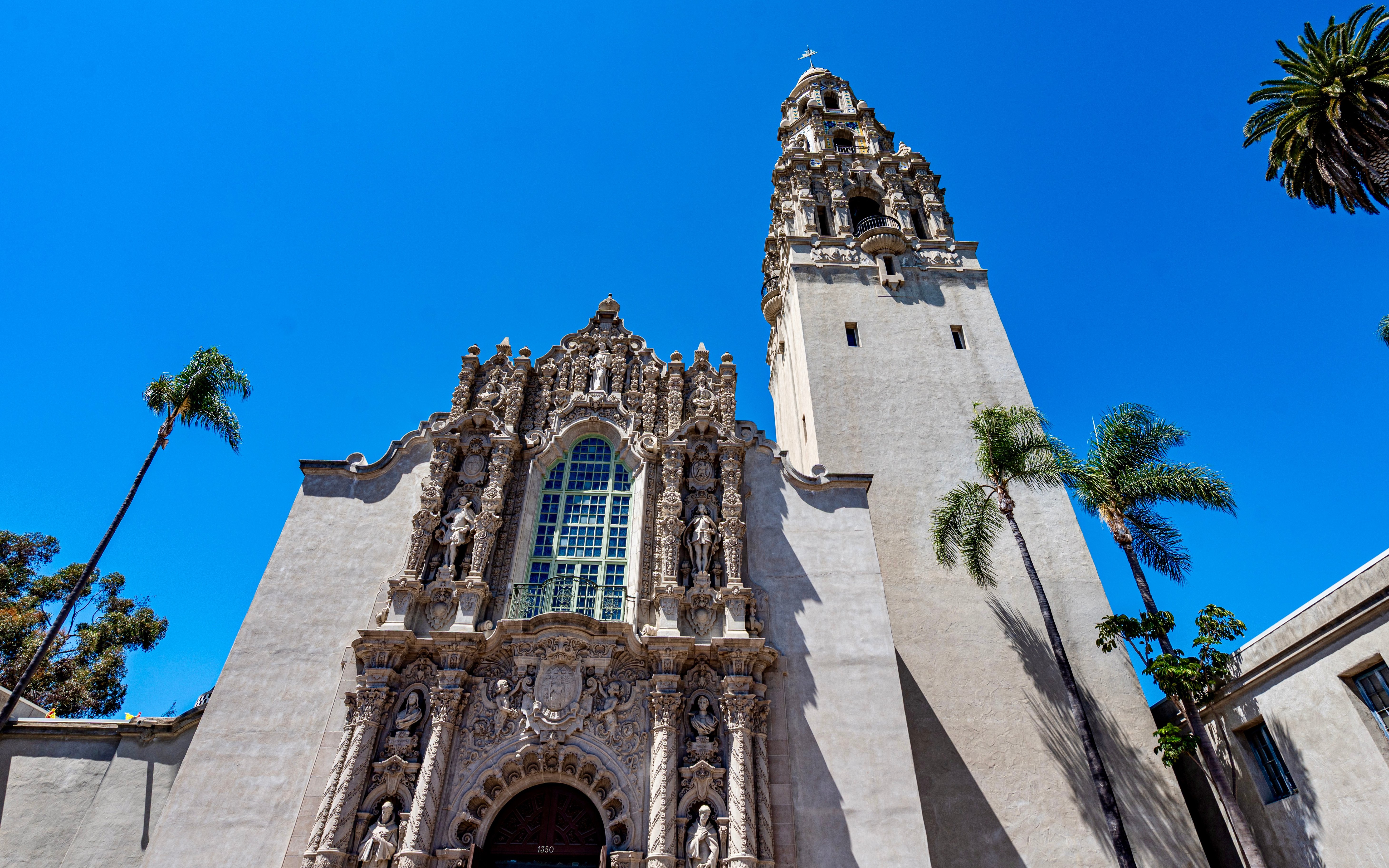 Balboa Park's California Tower and ornate facade in San Diego, CA, under a clear summer sky.