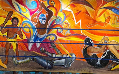 Lucha Libre mural with masked wrestlers in colorful action scene, Mexico.