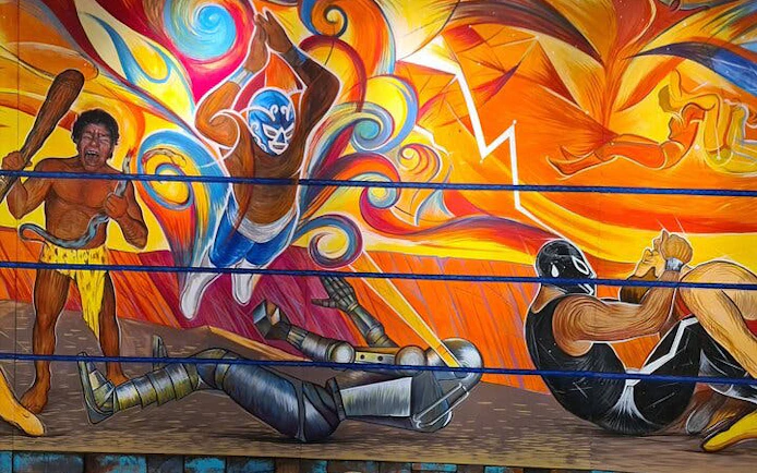Lucha Libre mural with masked wrestlers in colorful action scene, Mexico.