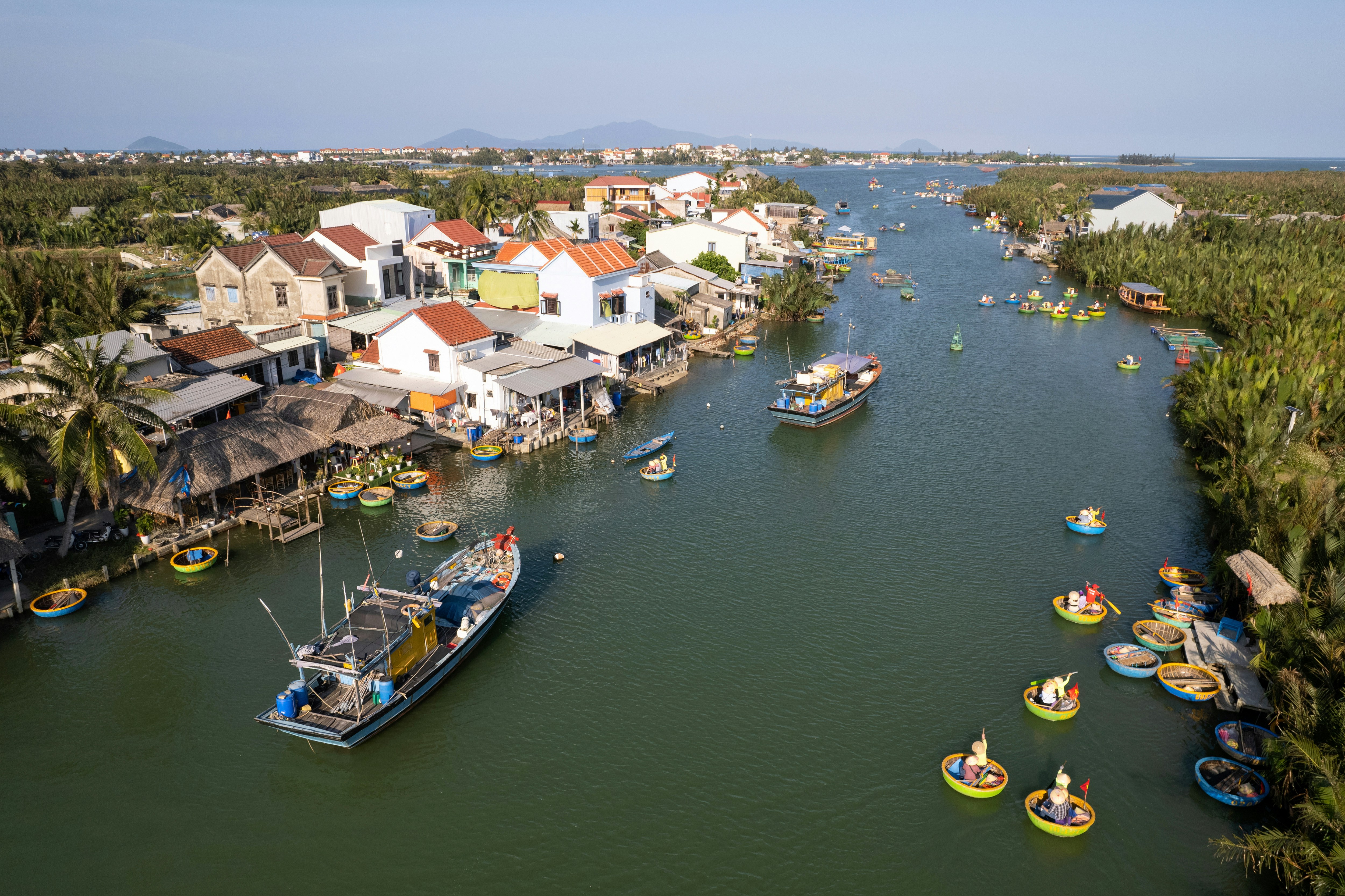 Aerial view of boats on Thu Bon River, Hoi An, Vietnam, with riverside houses.