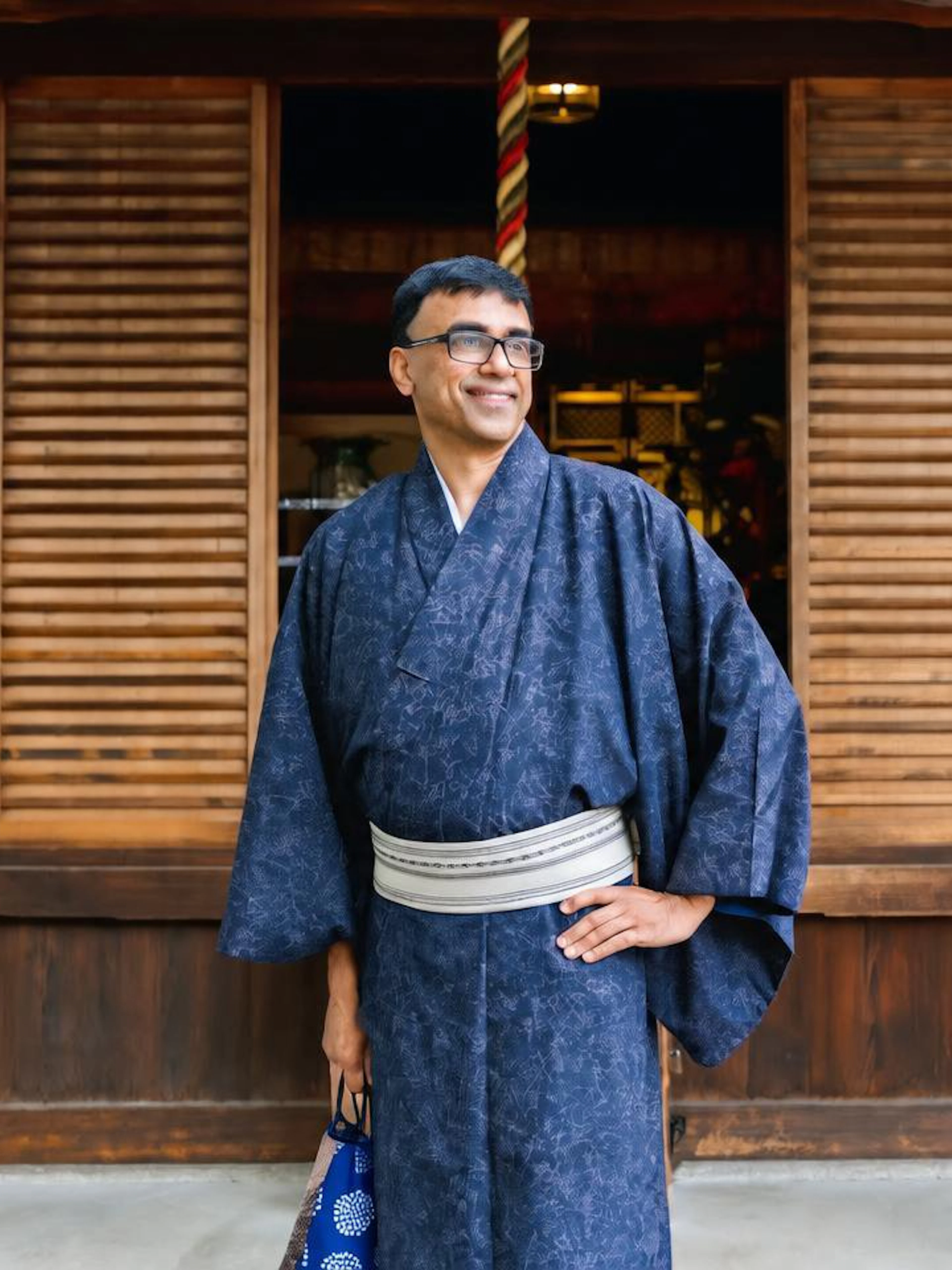 Man in traditional kimono standing in front of wooden building in Kyoto.