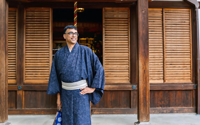 Man in traditional kimono standing in front of wooden building in Kyoto.