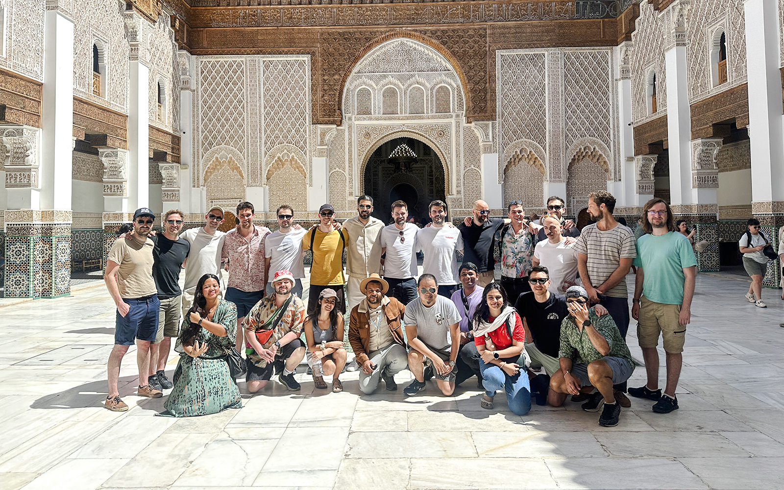 Group of tourists at Ben Youssef Madrasa courtyard in Marrakech, Morocco.