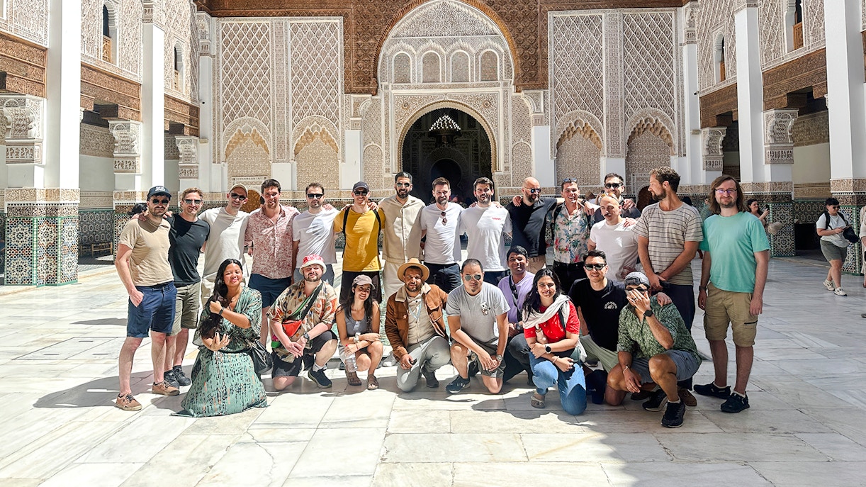 Group of tourists at Ben Youssef Madrasa courtyard in Marrakech, Morocco.