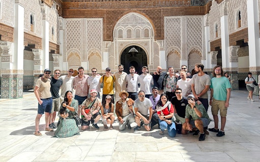 Group of tourists at Ben Youssef Madrasa courtyard in Marrakech, Morocco.