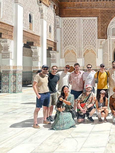 Group of tourists at Ben Youssef Madrasa courtyard in Marrakech, Morocco.