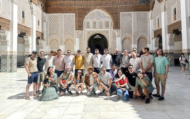 Group of tourists at Ben Youssef Madrasa courtyard in Marrakech, Morocco.
