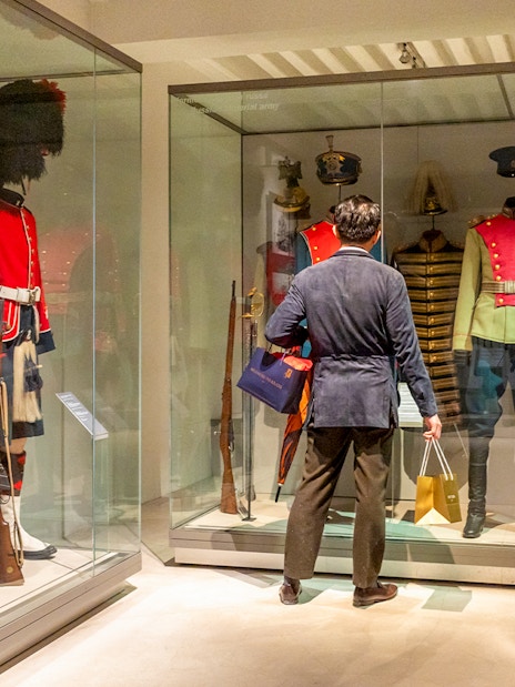 Army uniforms on display at The Army Museum with visitor observing.