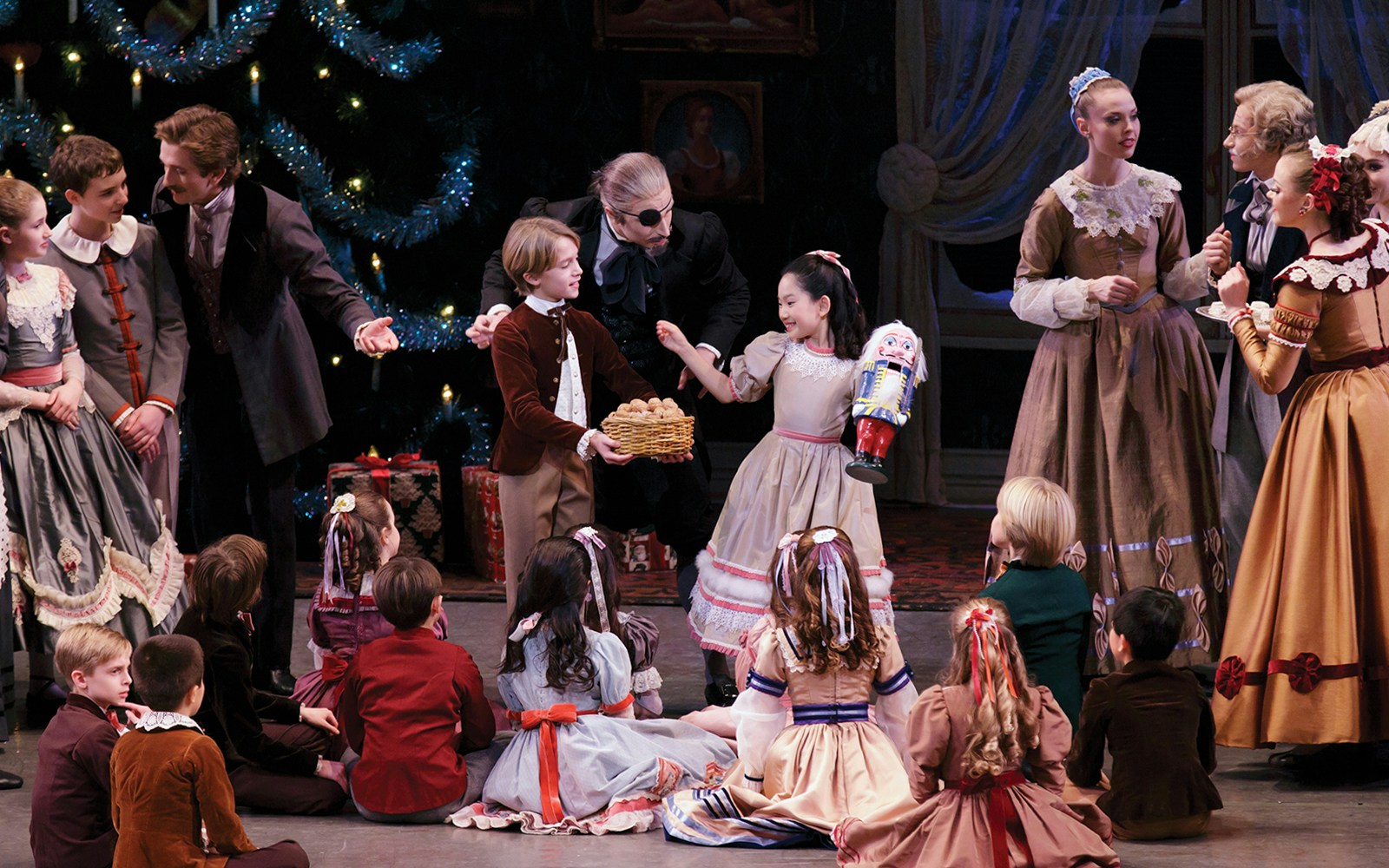 Children and adults in period costumes perform a scene from New York City Ballet's The Nutcracker.