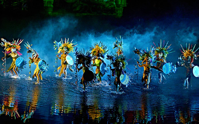 Performers in colorful costumes with shields and headdresses in "The Dream of Toledo" show.