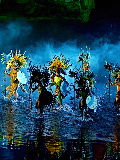 Performers in colorful costumes with shields and headdresses in "The Dream of Toledo" show.