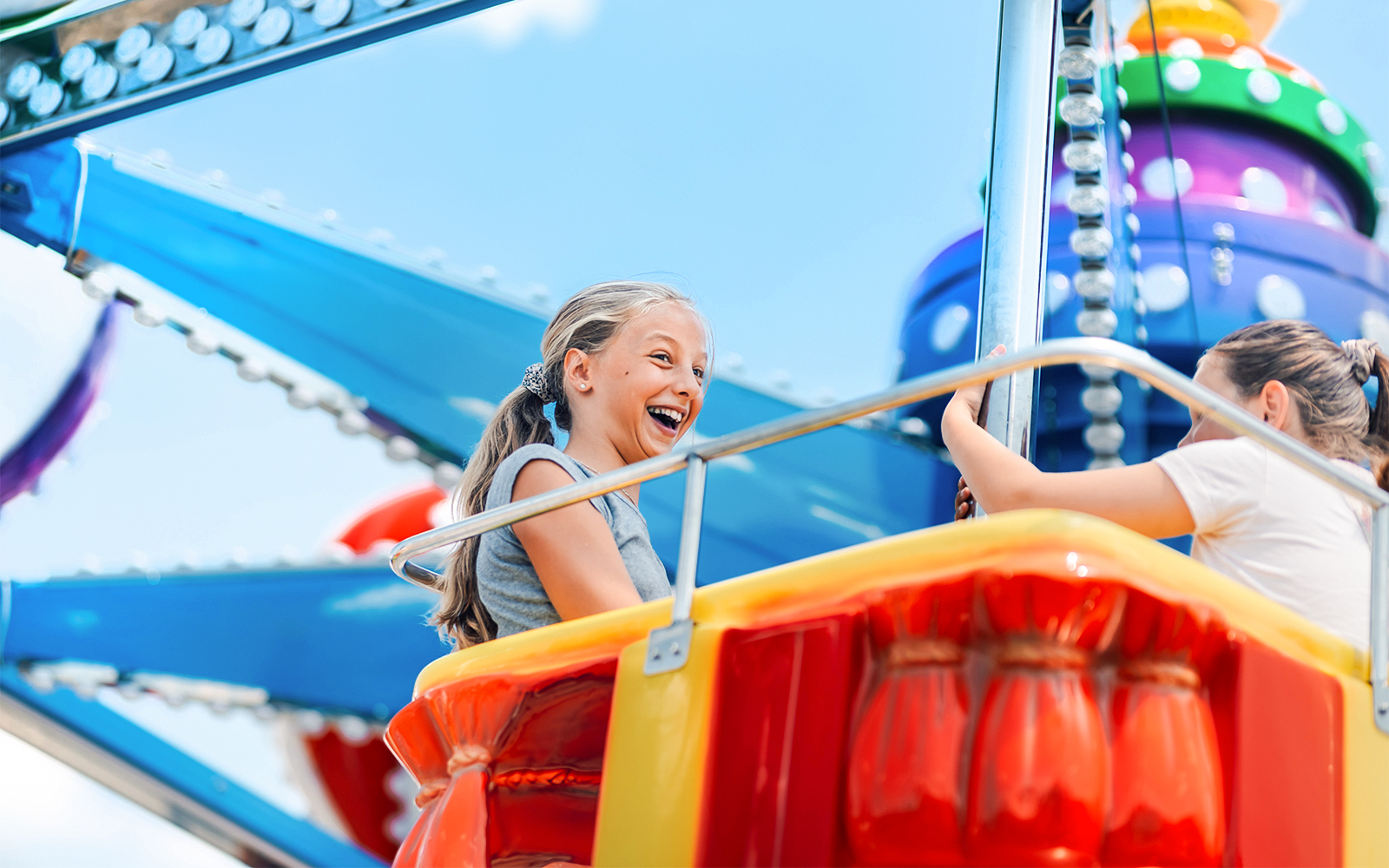 Girls enjoying a swing ride at an amusement park.