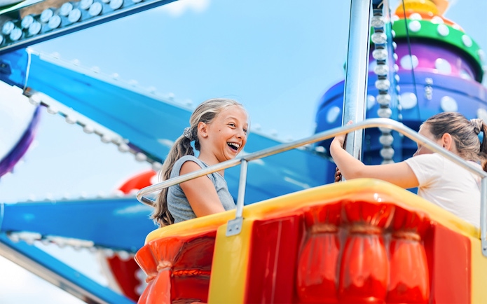 Girls enjoying a swing ride at an amusement park.