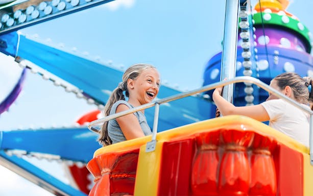 Girls enjoying a swing ride at an amusement park.