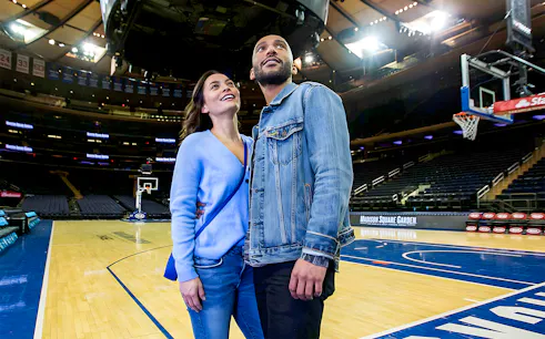 Couple exploring basketball court during Madison Square Garden guided tour.