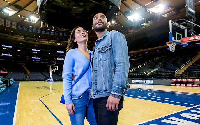 Couple exploring basketball court during Madison Square Garden guided tour.