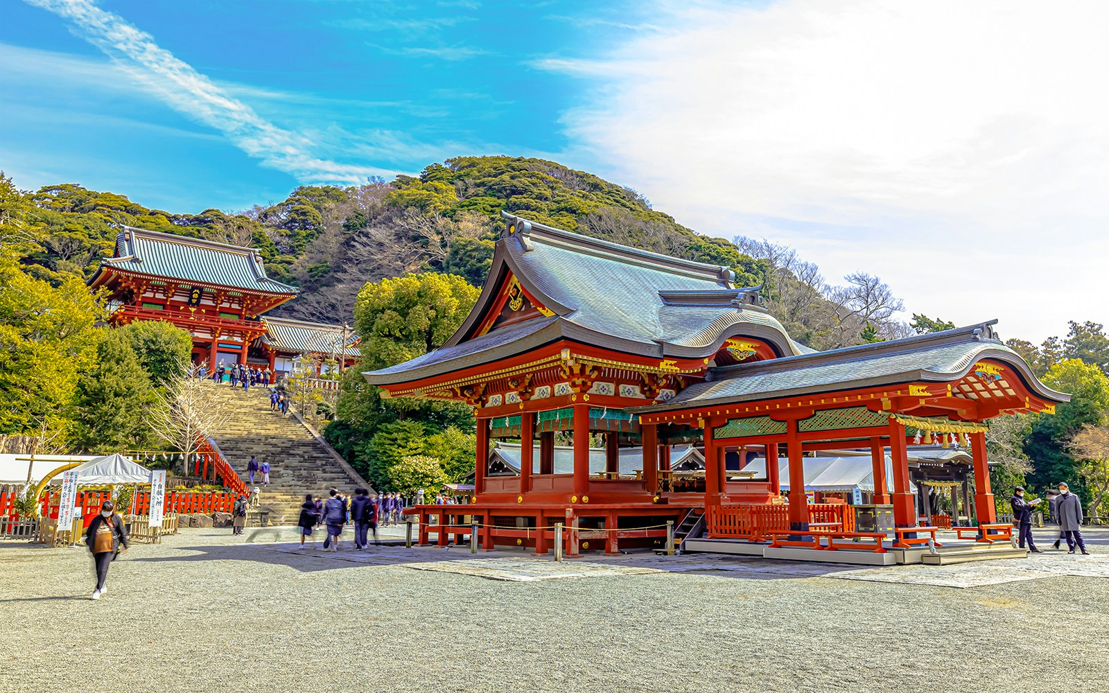 Tsurugaoka Hachimangu Shrine entrance with red torii gate and visitors in Kamakura, Japan.