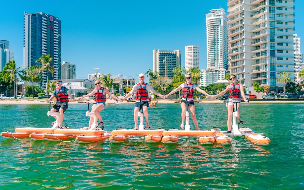 Tourists riding waterbikes on the Gold Coast with city skyline in the background.