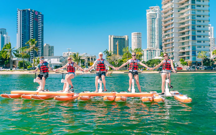 Tourists riding waterbikes on the Gold Coast with city skyline in the background.