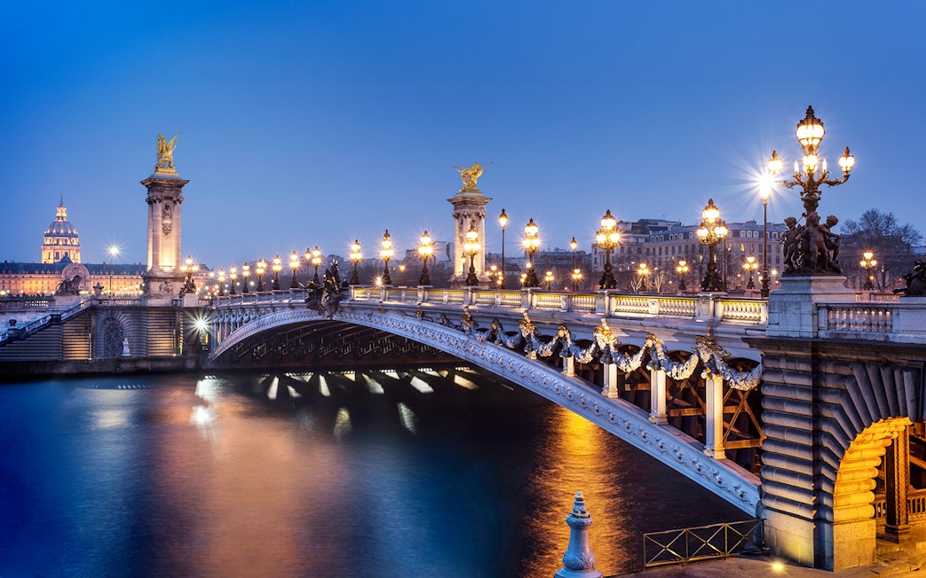 Pont Alexandre III illuminated at night, Paris, viewed from the Seine River.