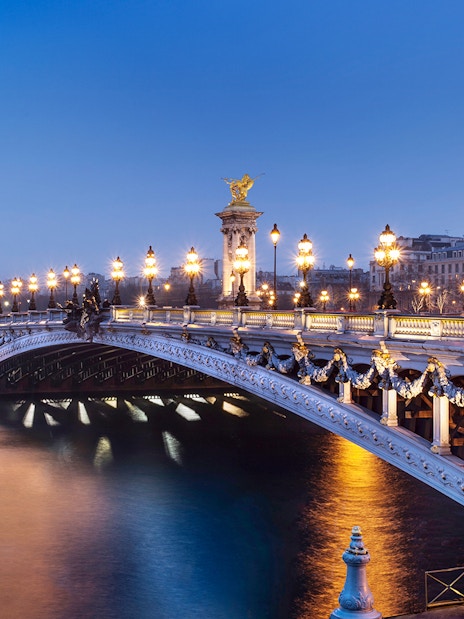 Pont Alexandre III illuminated at night, Paris, viewed from the Seine River.