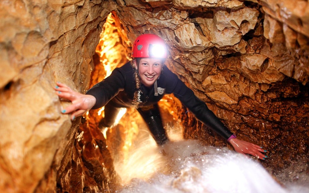 Caver exploring narrow passage during black water rafting in Waitomo cave.