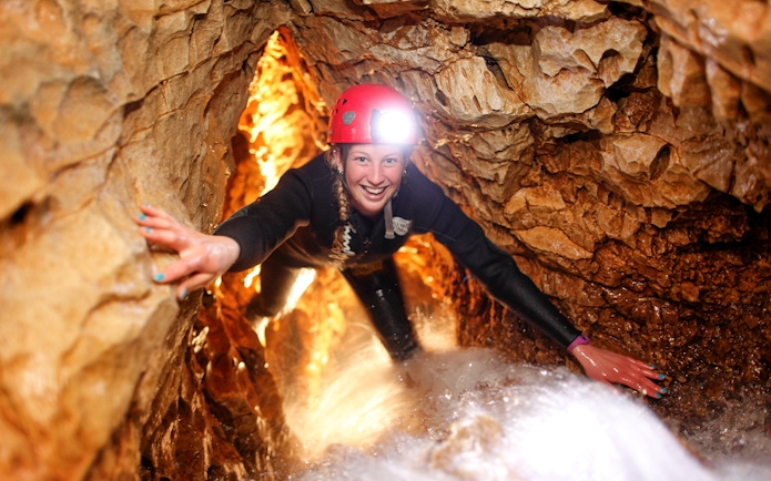 Caver exploring narrow passage during black water rafting in Waitomo cave.
