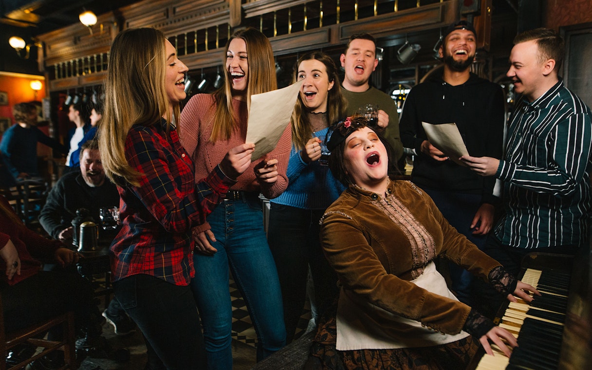 Group singing around a piano at London Dungeon Tavern.