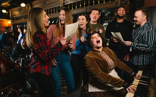 Group singing around a piano at London Dungeon Tavern.