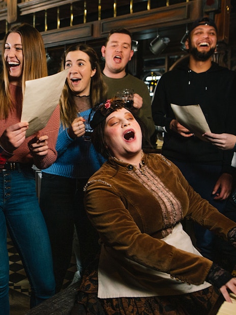 Group singing around a piano at London Dungeon Tavern.