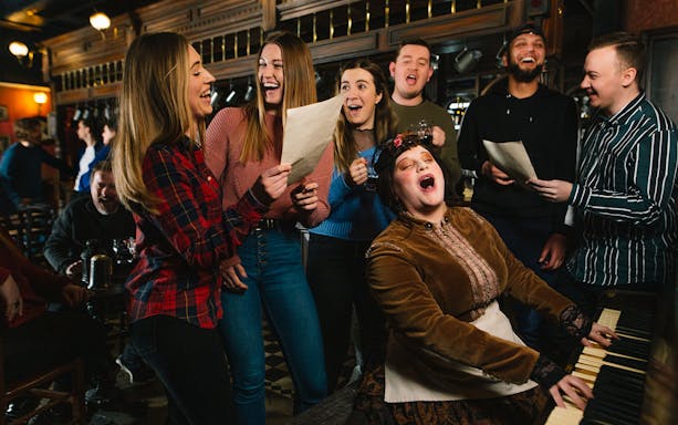 Group singing around a piano at London Dungeon Tavern.