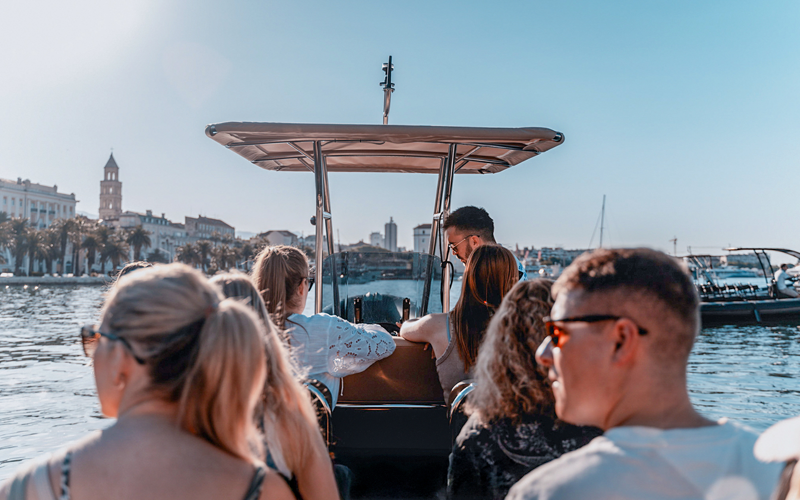 Guests enjoying a speedboat ride with cityscape views in the background.
