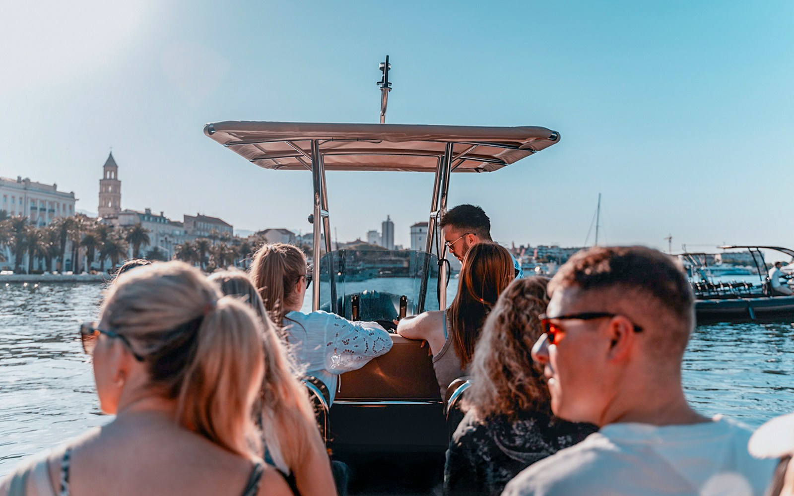 Guests enjoying a speedboat ride with cityscape views in the background.