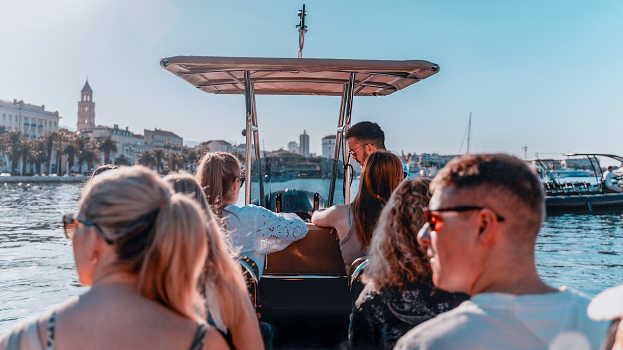 Guests enjoying a speedboat ride with cityscape views in the background.