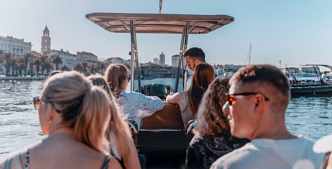 Guests enjoying a speedboat ride with cityscape views in the background.