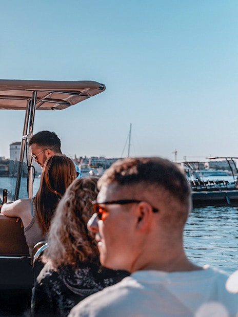 Guests enjoying a speedboat ride with cityscape views in the background.