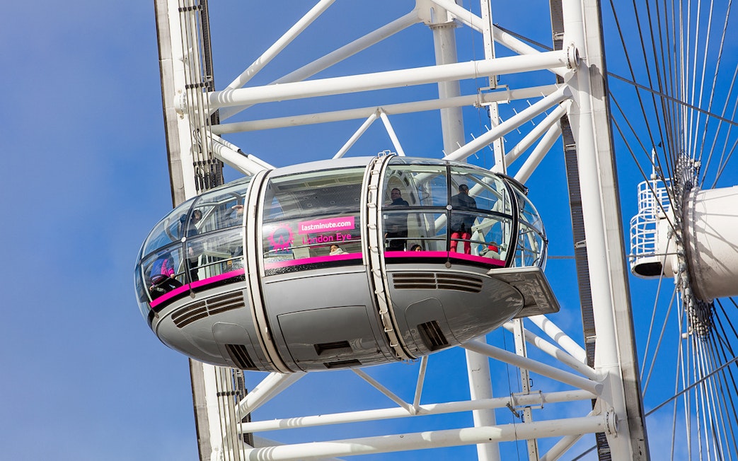 London Eye pod with passengers against a blue sky.
