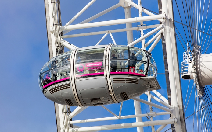 London Eye pod with passengers against a blue sky.