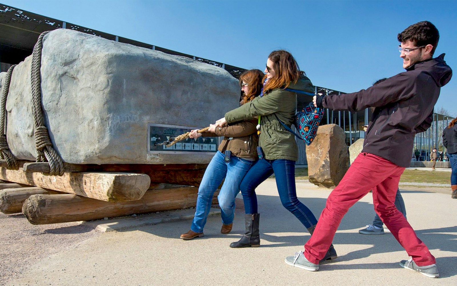 Visitors pulling a large stone replica at Stonehenge exhibit during half-day tour from London.