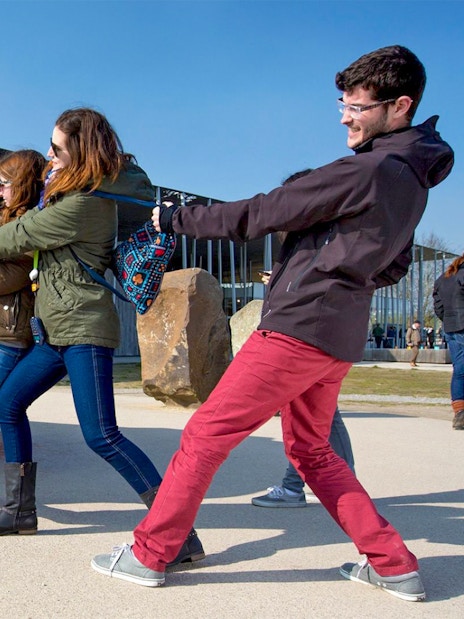 Visitors pulling a large stone replica at Stonehenge exhibit during half-day tour from London.