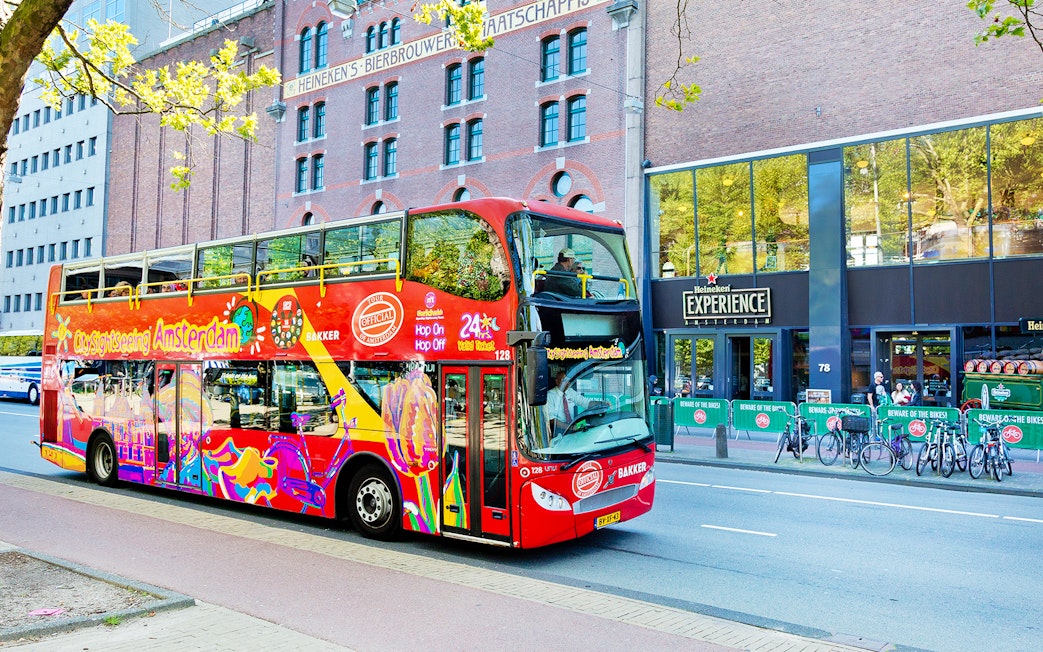 Red double-decker bus on Amsterdam Hop-On Hop-Off tour near Heineken Experience.