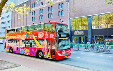 Red double-decker bus on Amsterdam Hop-On Hop-Off tour near Heineken Experience.