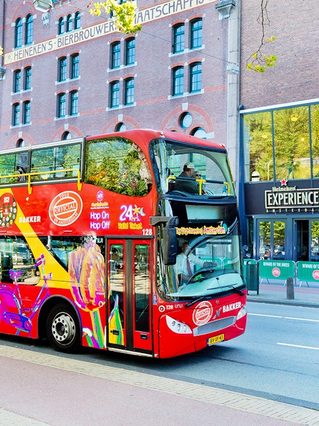 Red double-decker bus on Amsterdam Hop-On Hop-Off tour near Heineken Experience.