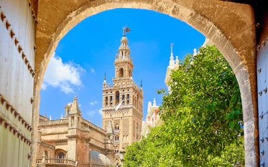 Seville's Giralda tower framed by an archway with clear blue sky.