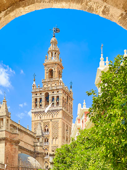 Seville's Giralda tower framed by an archway with clear blue sky.